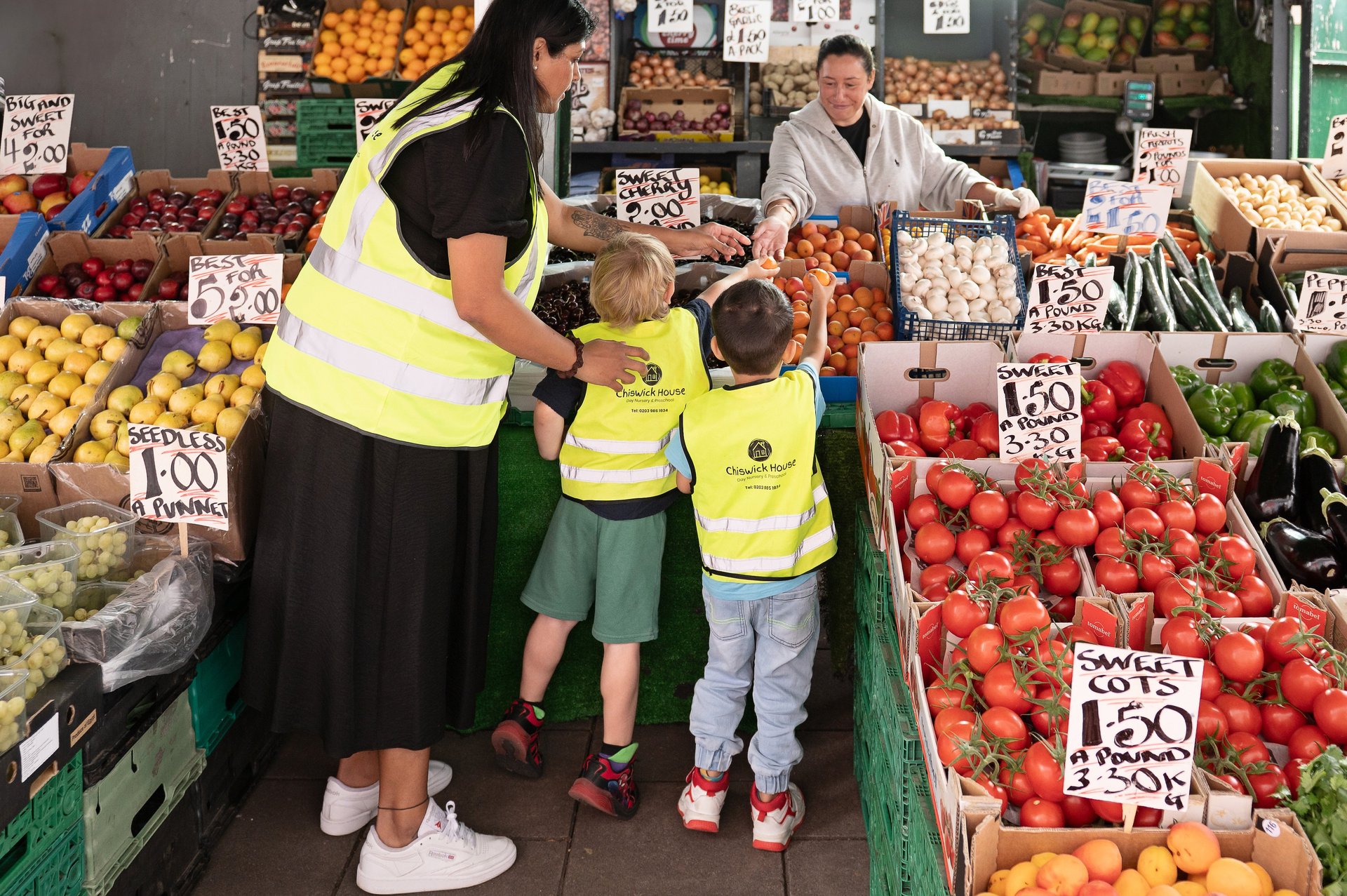 A woman and two kids browse colourful fruits and veggies at a lively market