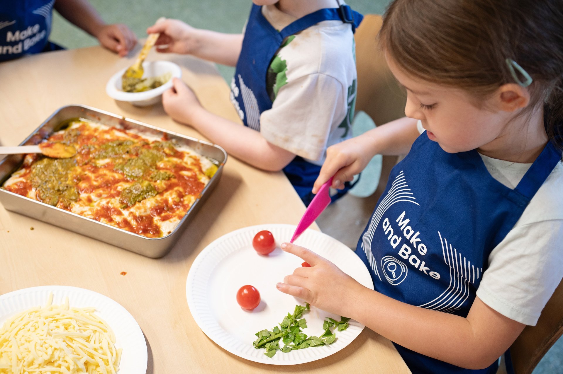 Kids in colourful aprons happily cooking together in a bright kitchen